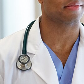Estetoscópio Littmann corretamente colocado de fora do colarinho de uma bata branca, impedindo que o tubo toque no pescoço do médico.