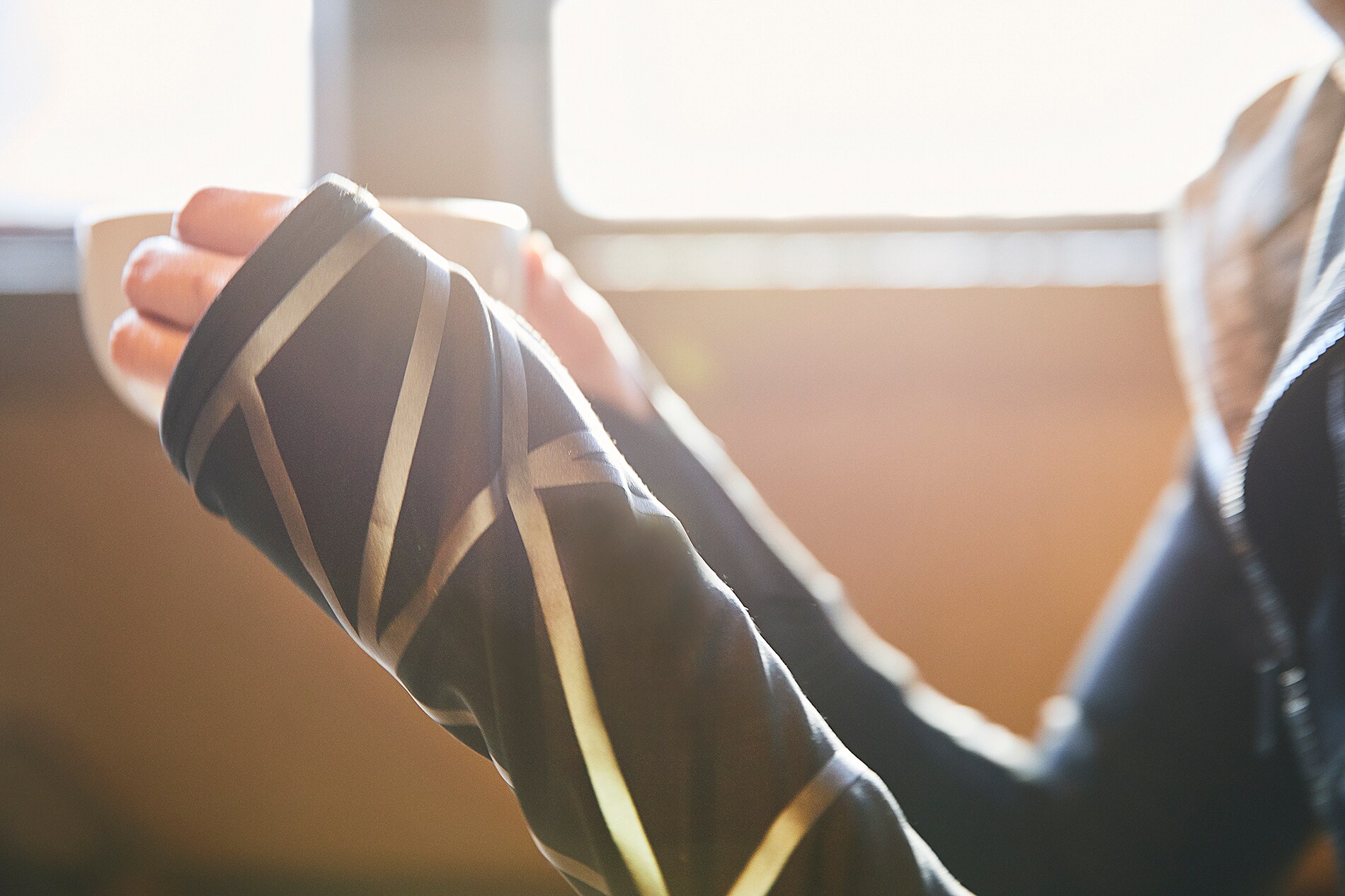 Woman having coffee, close up of Scotchlite Black Stretch Reflective on sleeve of woman with coffee.
