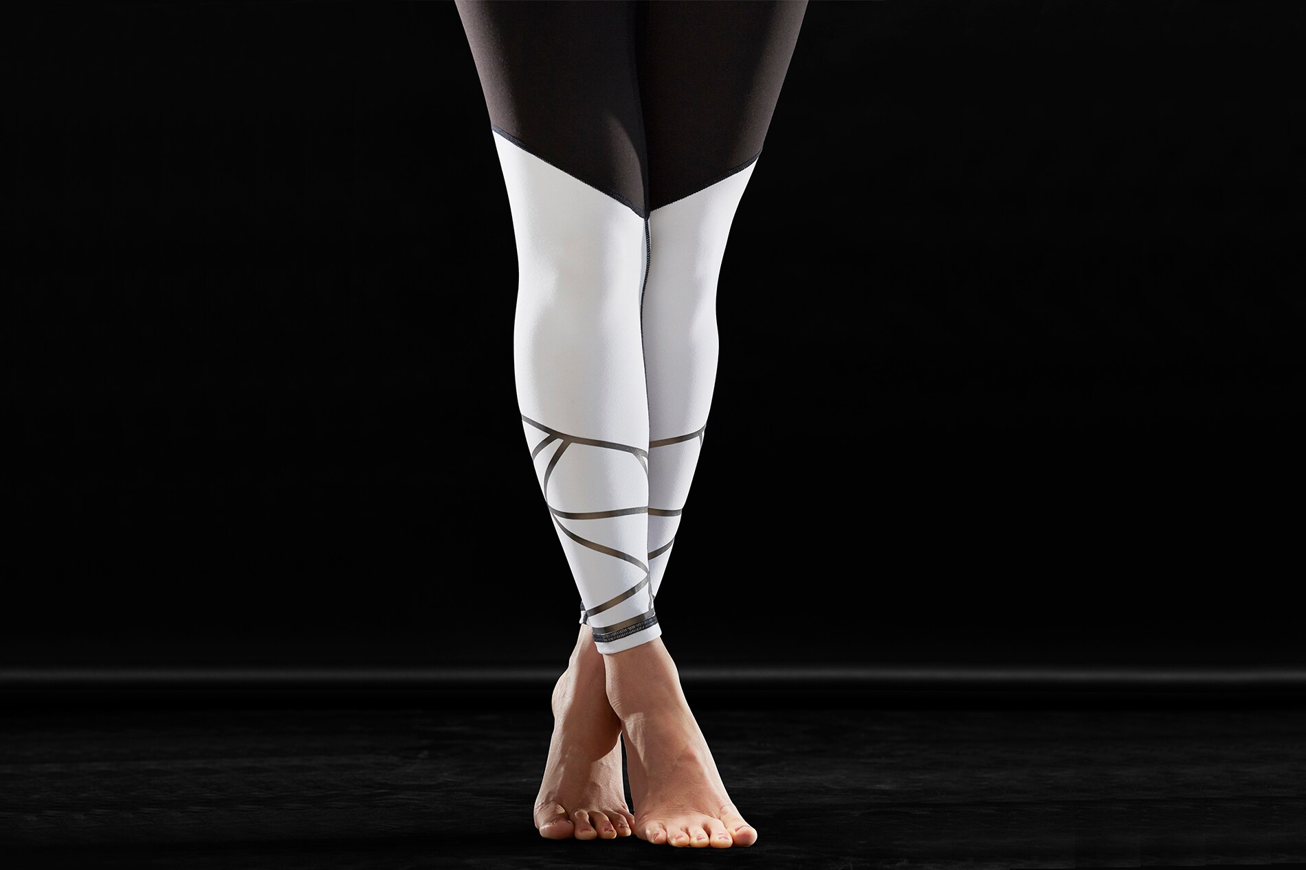 Woman wearing white tights with Scotchlite Black Stretch Reflective standing up on tip toes.
