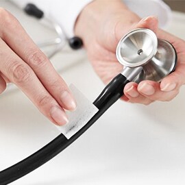Mãos a limparem o tubo de um estetoscópio Littmann utilizando um cotonete embebido em álcool.