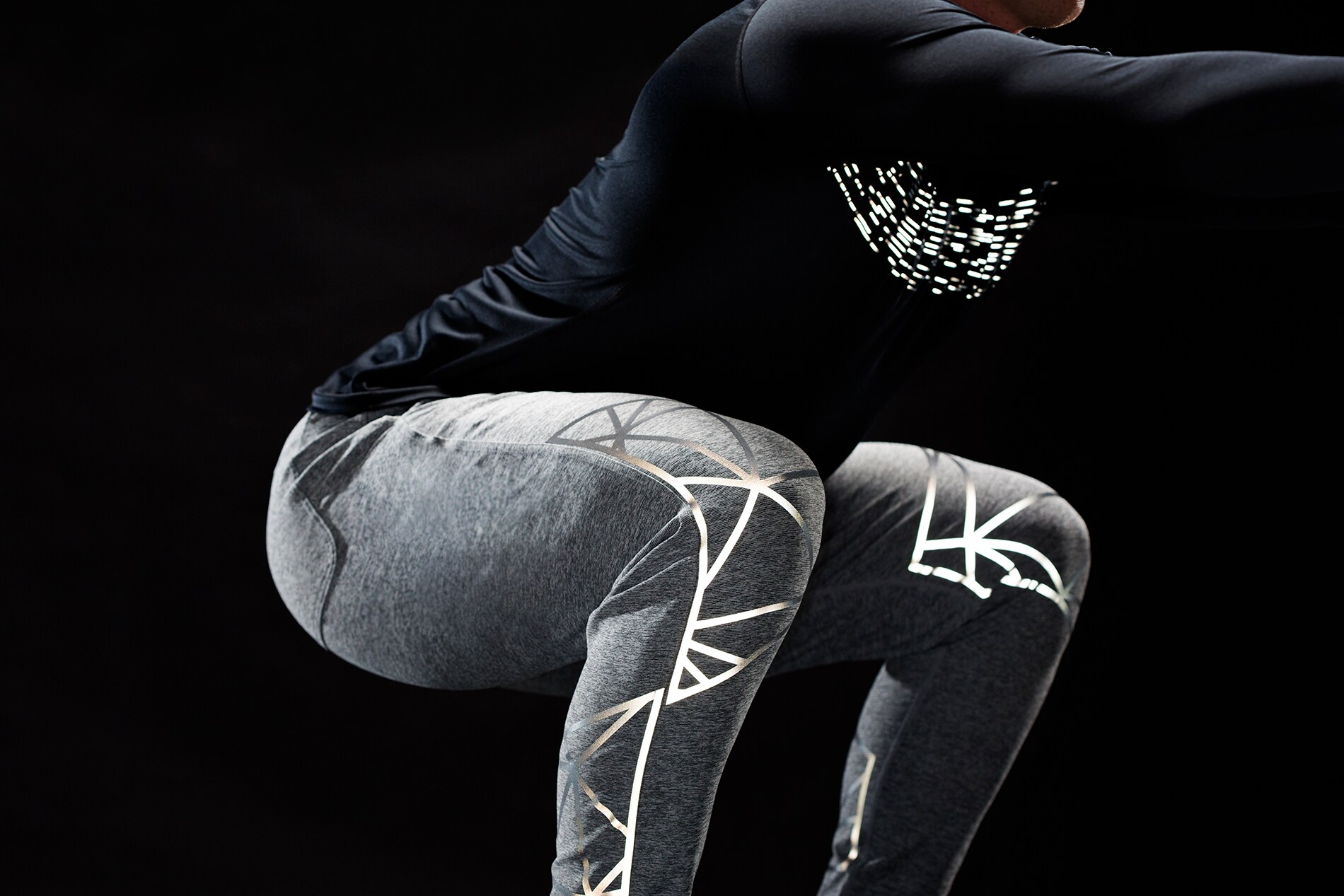 Man doing squat exercise with illuminated 3M Scotchlite Black Stretch Reflective stretching over knees and on chest.
