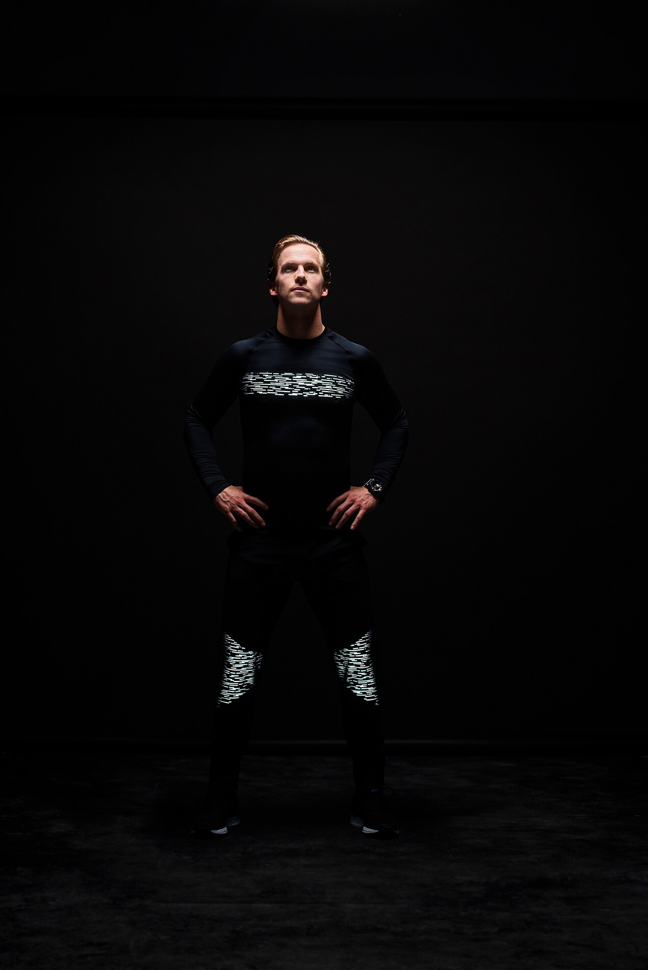 Man standing in dark wearing shirt, pants illuminated by 3M Scotchlite Black Stretch Reflective.
