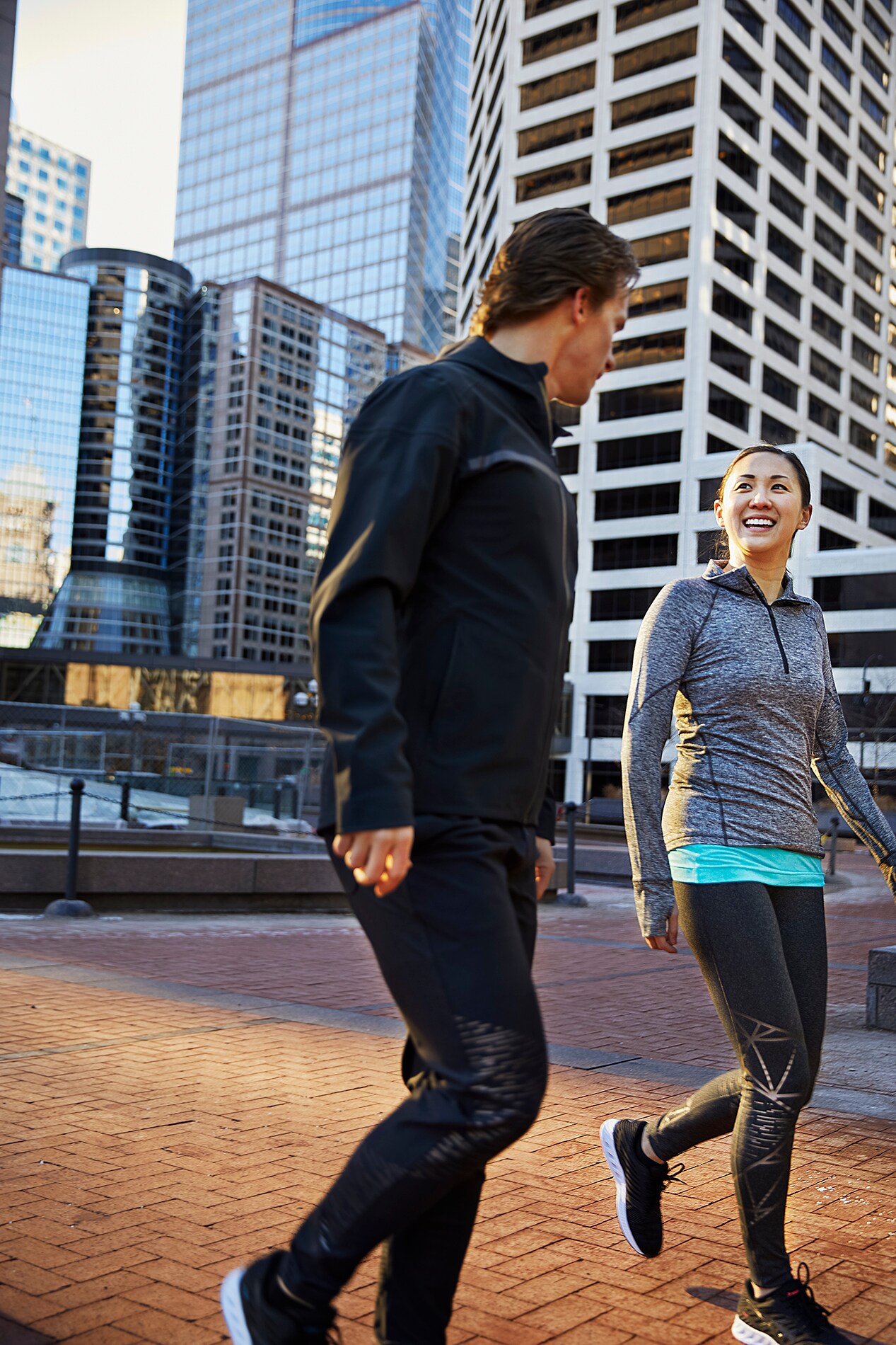 Man and woman in city walking, talking, exercising with 3M Scotchlite C790 Carbon Black Stretch Reflective Material.
