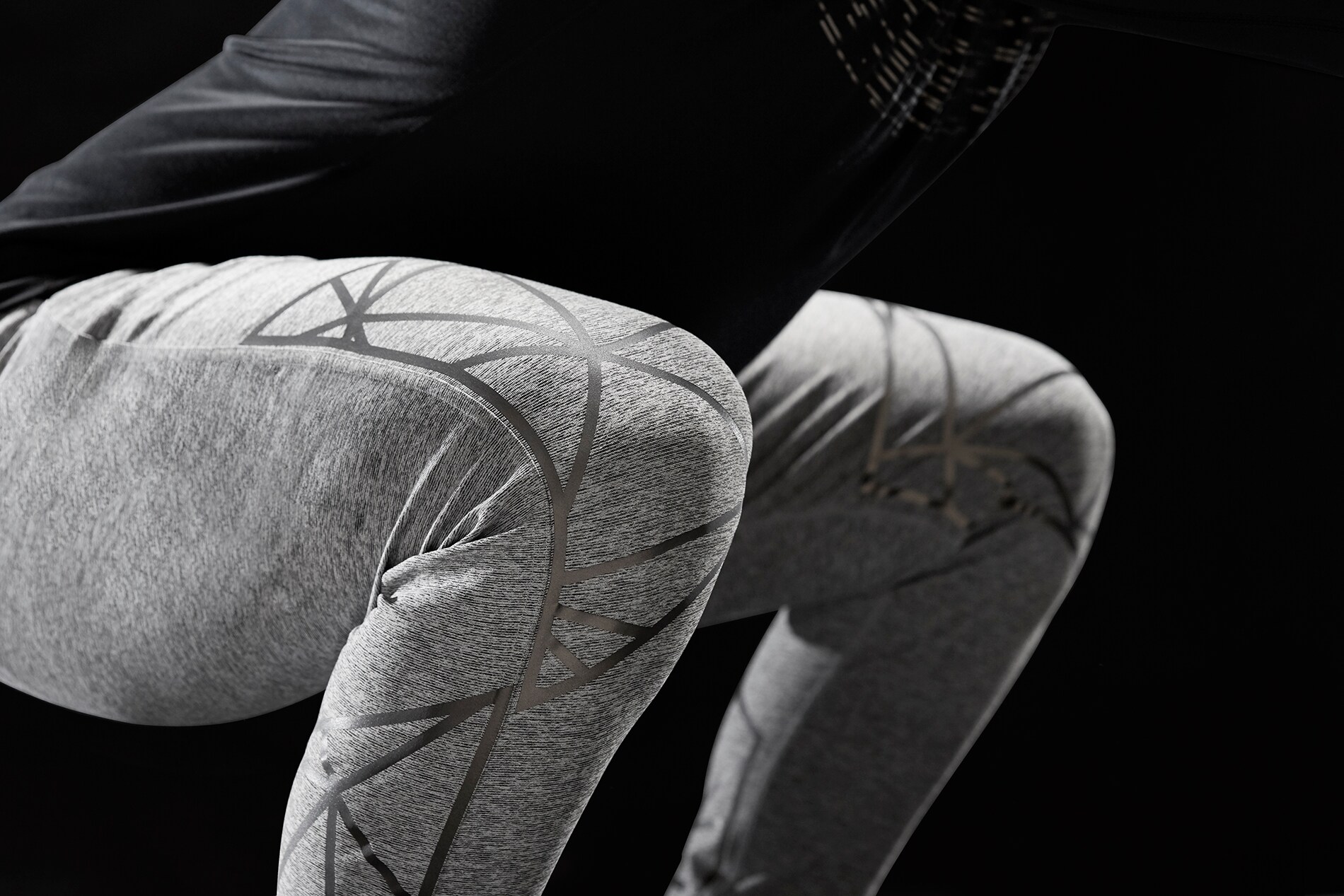 Man doing squat exercise with 3M Scotchlite Black Stretch Reflective stretching over knees not illuminated.
